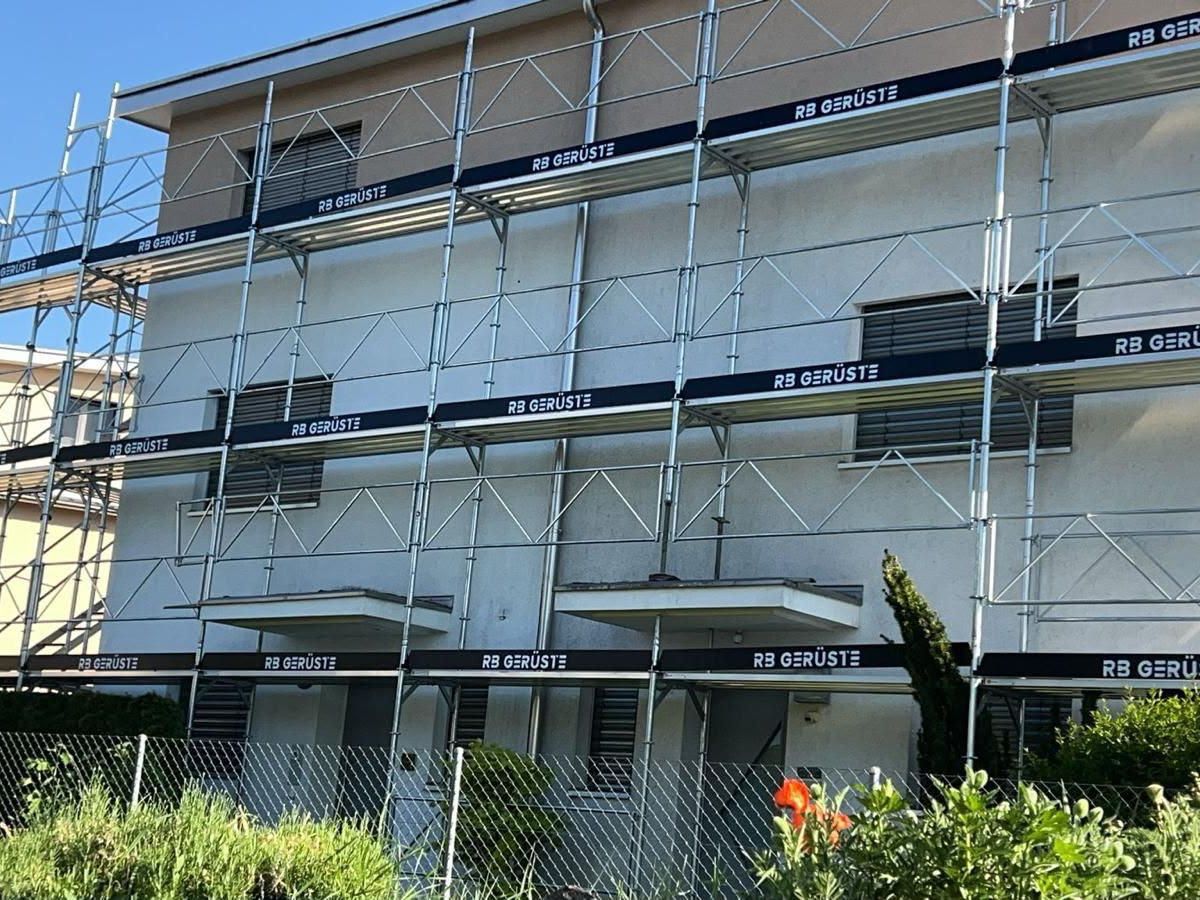 Fassadengerüst von RB Gerüste an einem Wohnhaus im Bestand, Bordbretter mit Firmenschriftzug